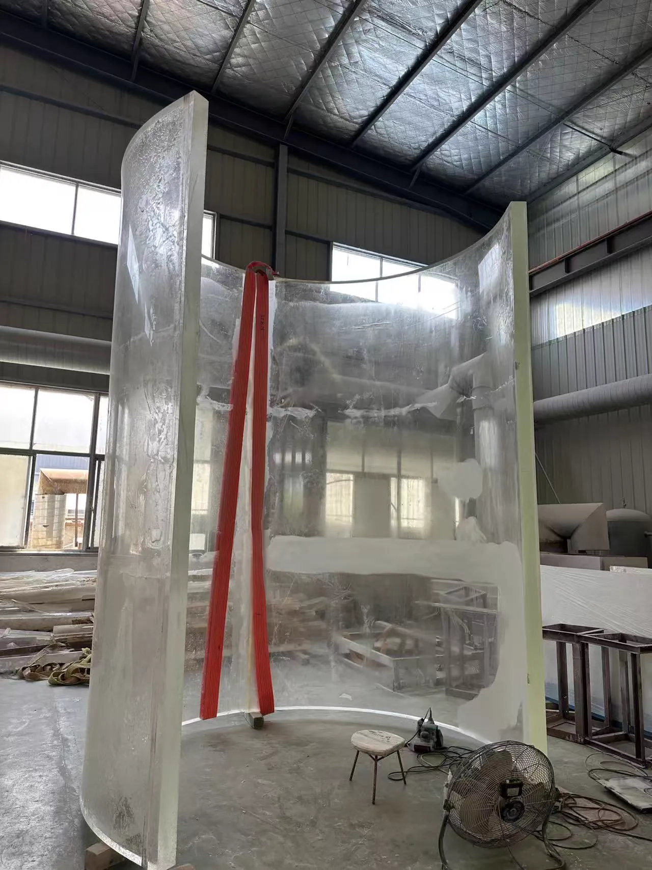 Tall transparent acrylic panel being formed into a compound curve in the workshop