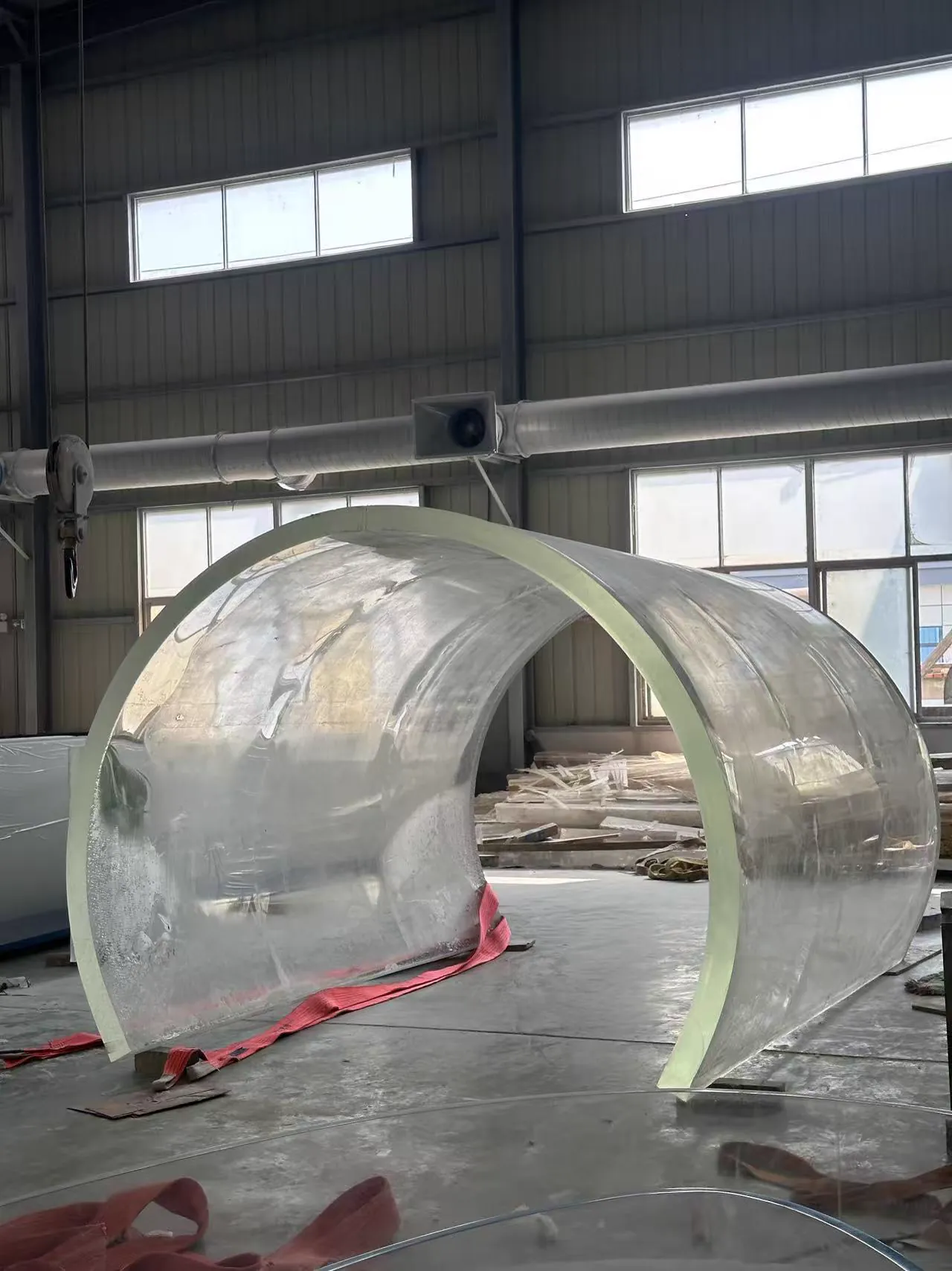 Completed transparent curved acrylic shell resting on the workshop floor