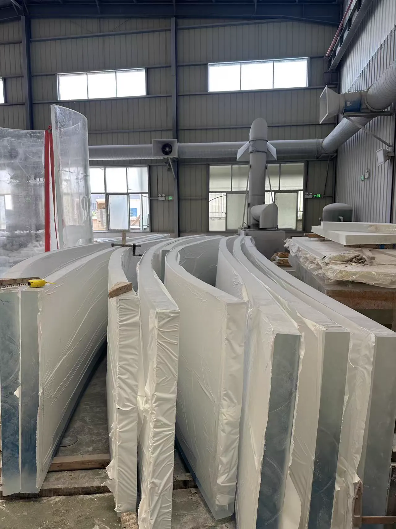 Protected curved acrylic components staged for production