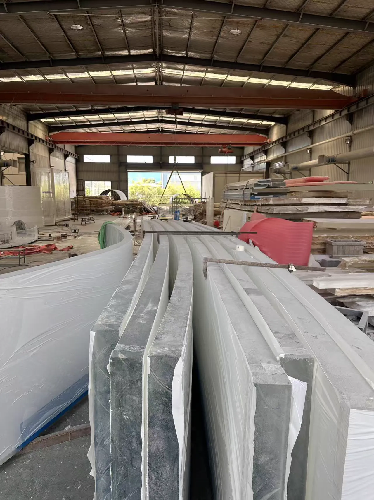 Large acrylic components arranged across the production workshop